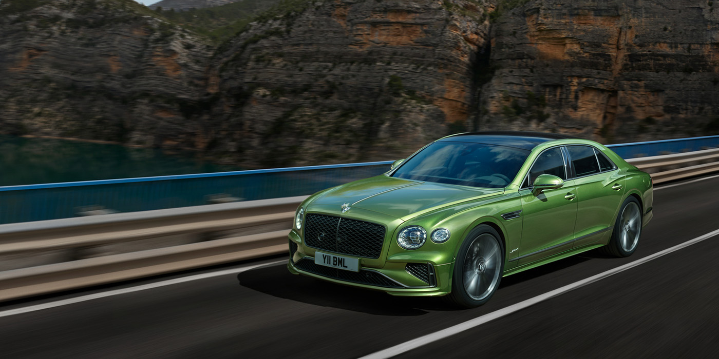Bentley Suomi Bentley New Flying Spur Speed v8 hybrid sedan driving dynamically on a mountain road in Tourmaline Green paint