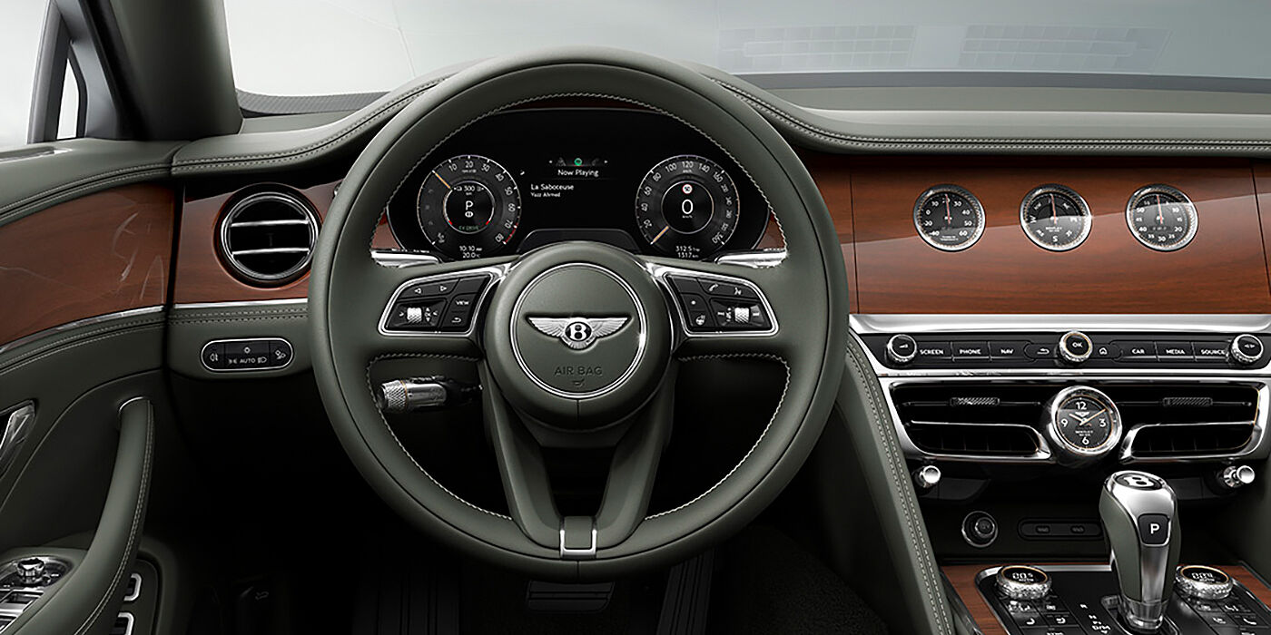 Bentley Suomi New Bentley Flying Spur sedan front cabin in Cumbrian Green hide and Crown Cut walnut veneer showing steering wheel and Rotating Display with three clocks on face